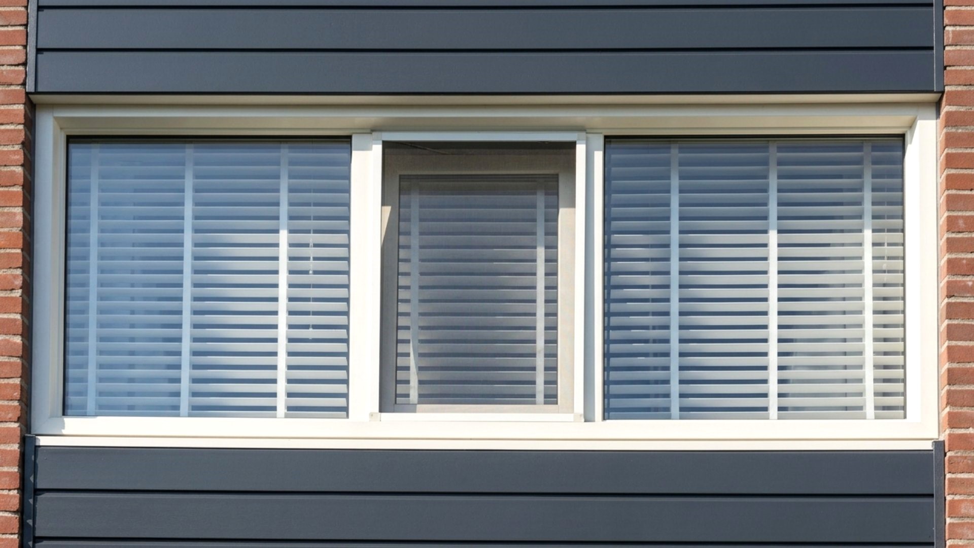 Keralit sponningdeel 143 antraciet toegepast als gevelbekleding rondom een raam met strakke horizontale lijnen