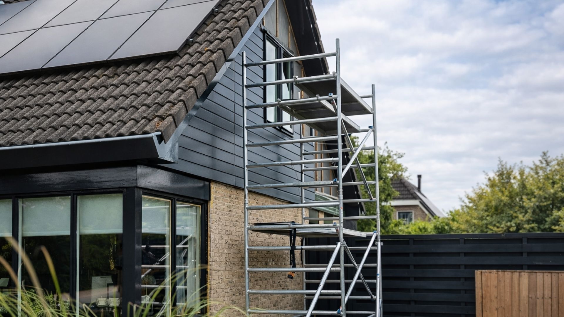 Keralit 143 zwartgrijs gevelbekleding Keralit 143 zwartgrijs gevelbekleding op woning tijdens montage met steiger
