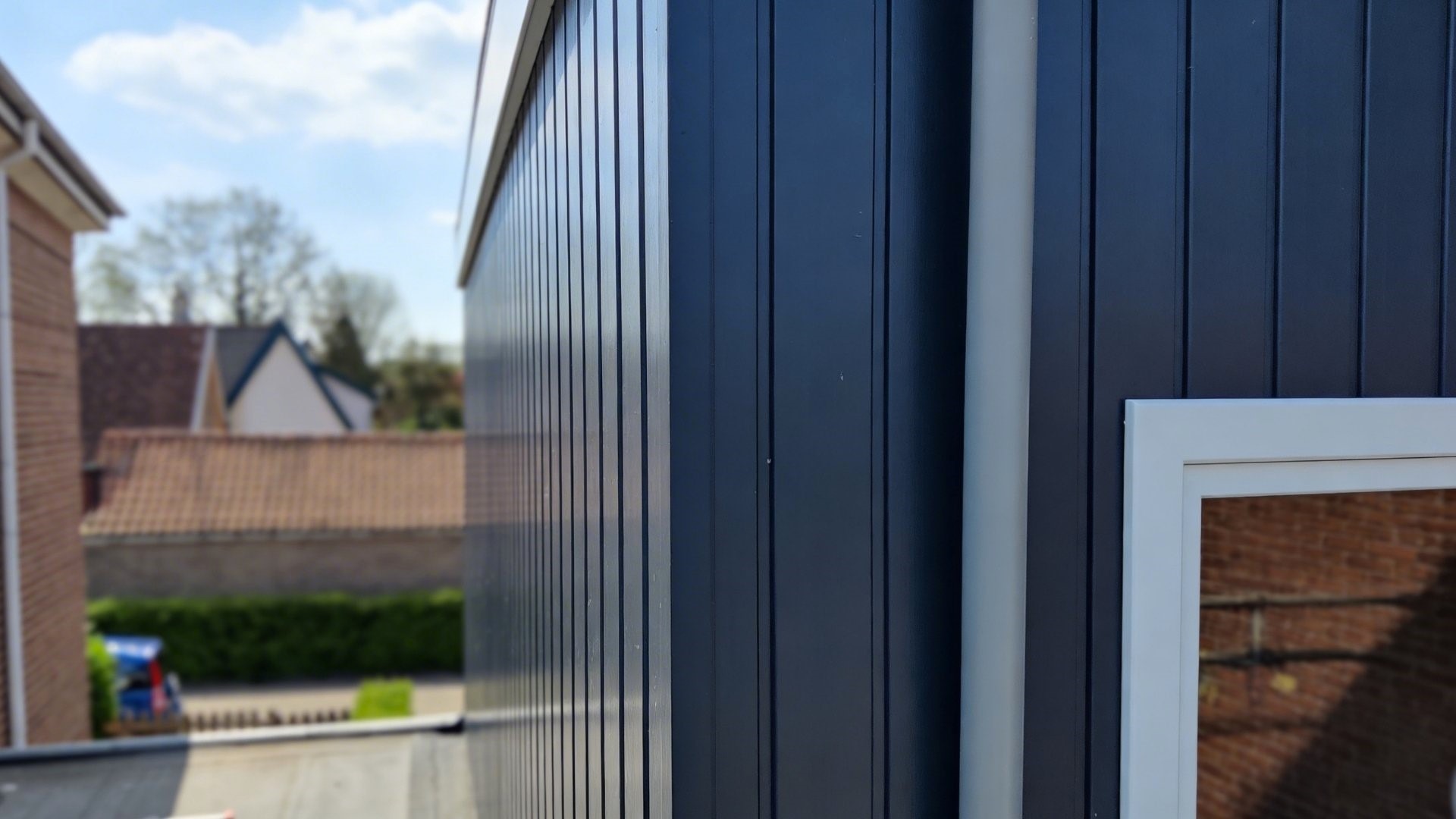 VinyPlus antraciet verticale gevelbekleding in detail bij raam en regenpijp