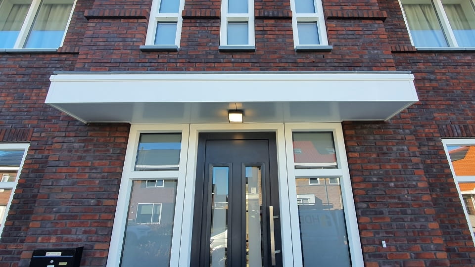 Keralit dakrand sierlijst in wit op woninggevel met entree